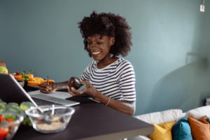 Smiling woman preparing a healthy meal at home with fresh fruits and vegetables on the counter, representing clean eating and wellness for women over 40.