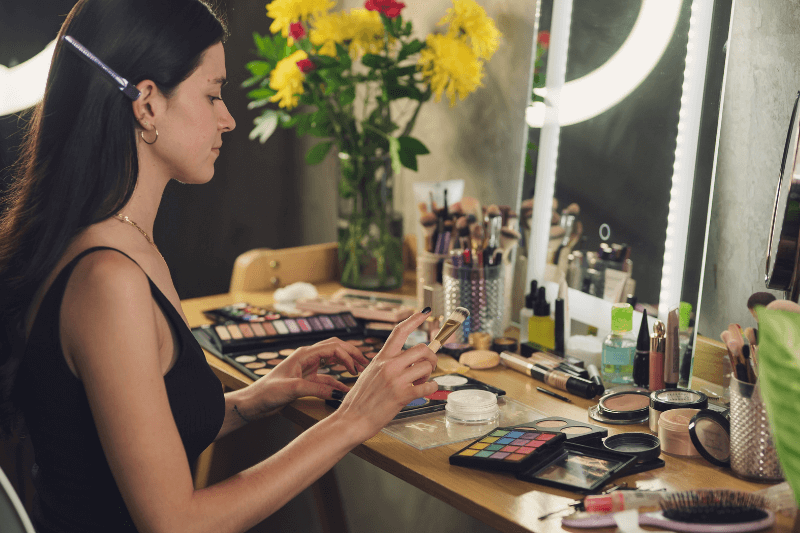 Midlife woman applying makeup in front of a mirror, representing everyday cosmetic use
